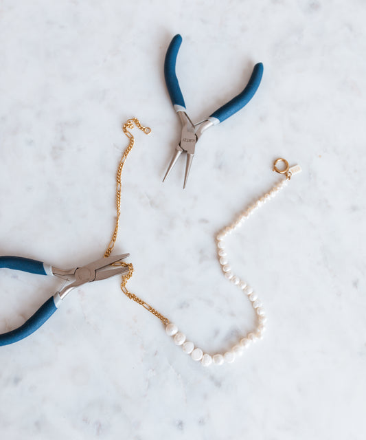 A pair of WALD Berlin pliers and a WALD Berlin pearl necklace on a table in Germany.