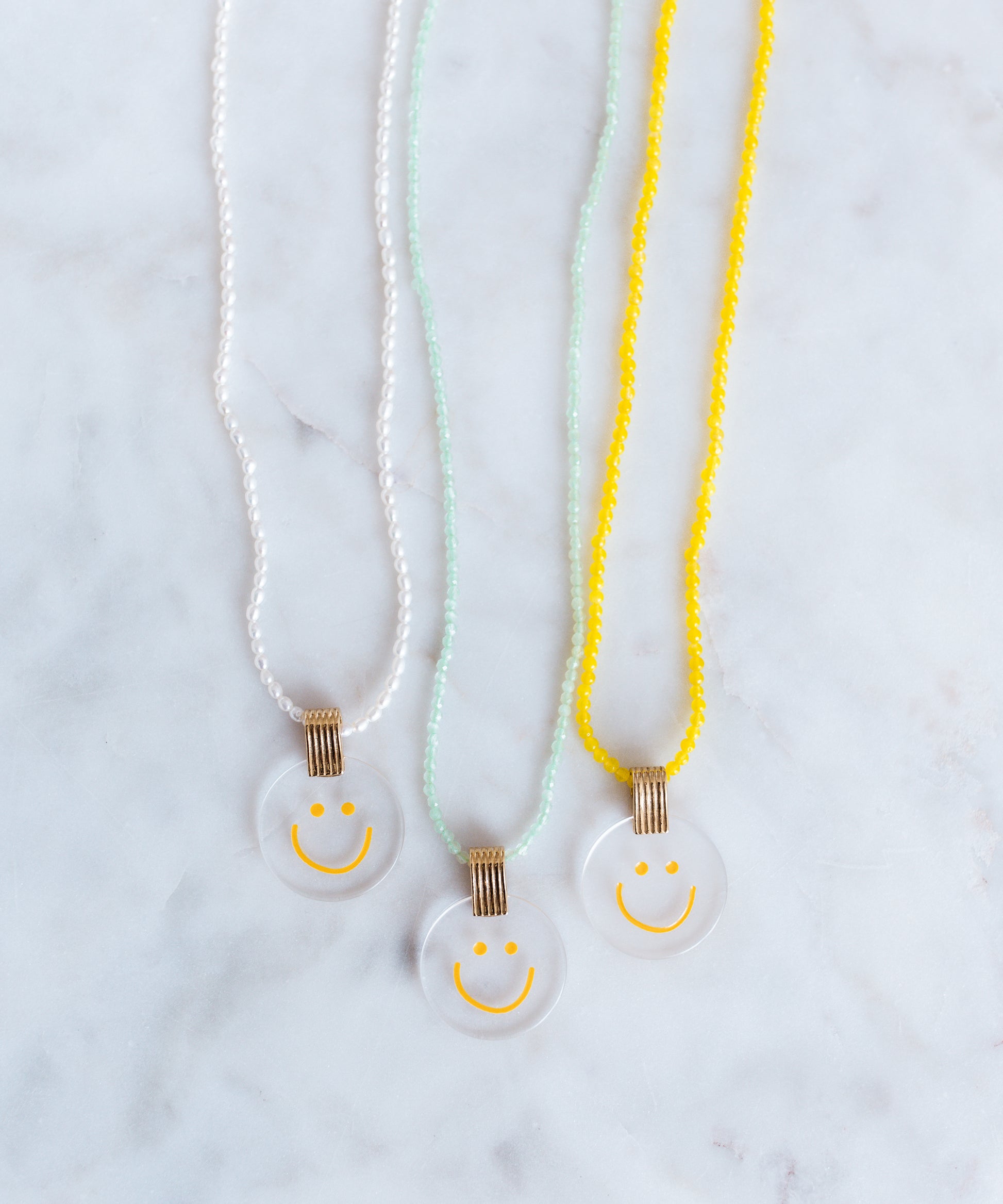 Three jewelry necklaces from WALD Berlin, featuring a smilie dude pearl medaillon design.