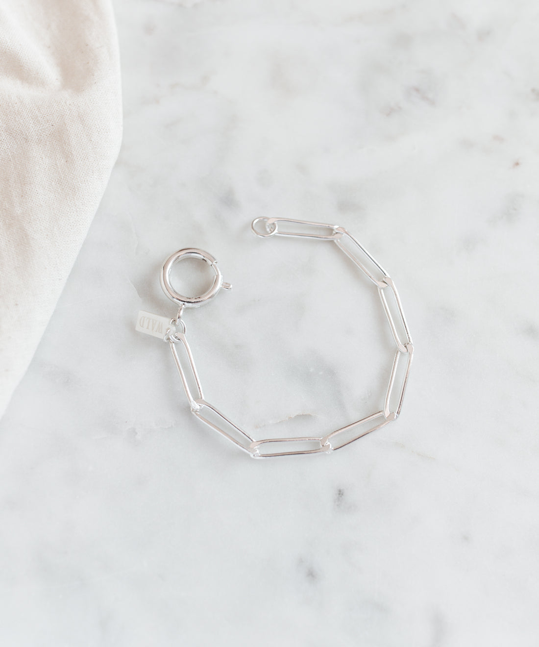 The SAMPLE SALE Ashley Bracelet Silver by WALD Berlin features a silver-plated chain and oversized clasp, shown on a white marble surface.