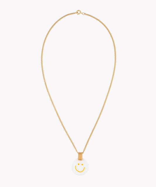 The Smilie Dude Medaillon Gold Necklace by WALD Berlin is an 18k gold-plated chain piece, showcasing a precisely crafted white circular medallion adorned with a yellow smiley face, made in Germany.