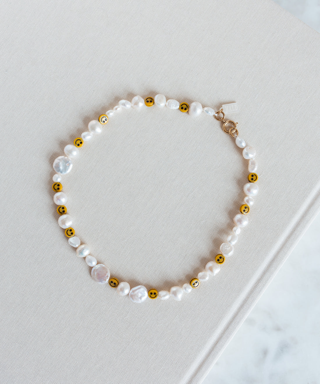 A Smilie Dude Pearl Necklace from WALD Berlin on top of a book in Germany.