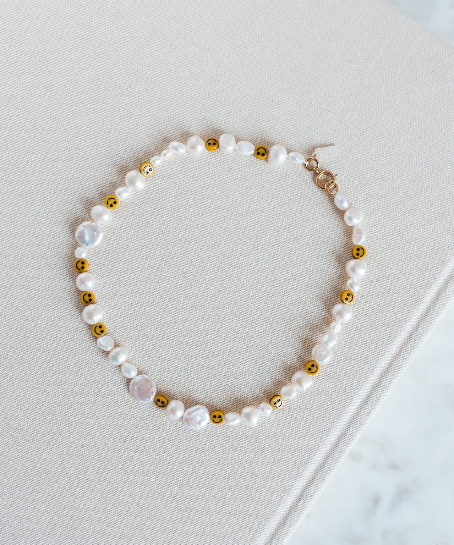 A Smilie Dude Pearl Necklace from WALD Berlin on top of a book in Germany.
