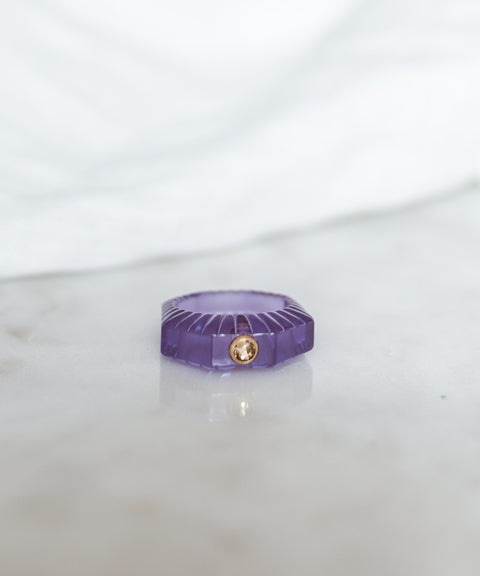 The SAMPLE SALE Shining Star Purple Ring by WALD Berlin features a hand-polished purple octagonal gemstone with a small round Swarovski stone, displayed on marble with a blurred white background.