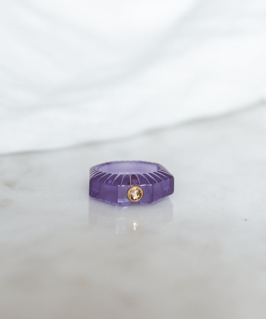 The SAMPLE SALE Shining Star Purple Ring by WALD Berlin features a hand-polished purple octagonal gemstone with a small round Swarovski stone, displayed on marble with a blurred white background.