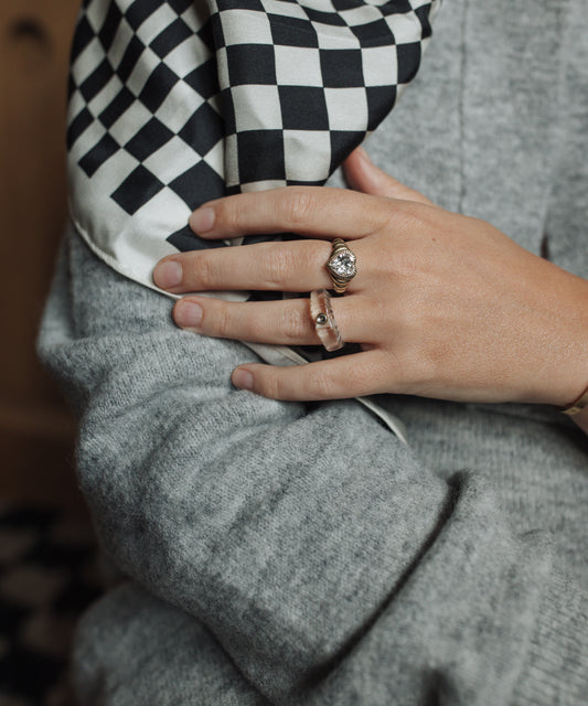 A woman wearing a checkered scarf and Be My Lover Gold Ring by WALD Berlin.