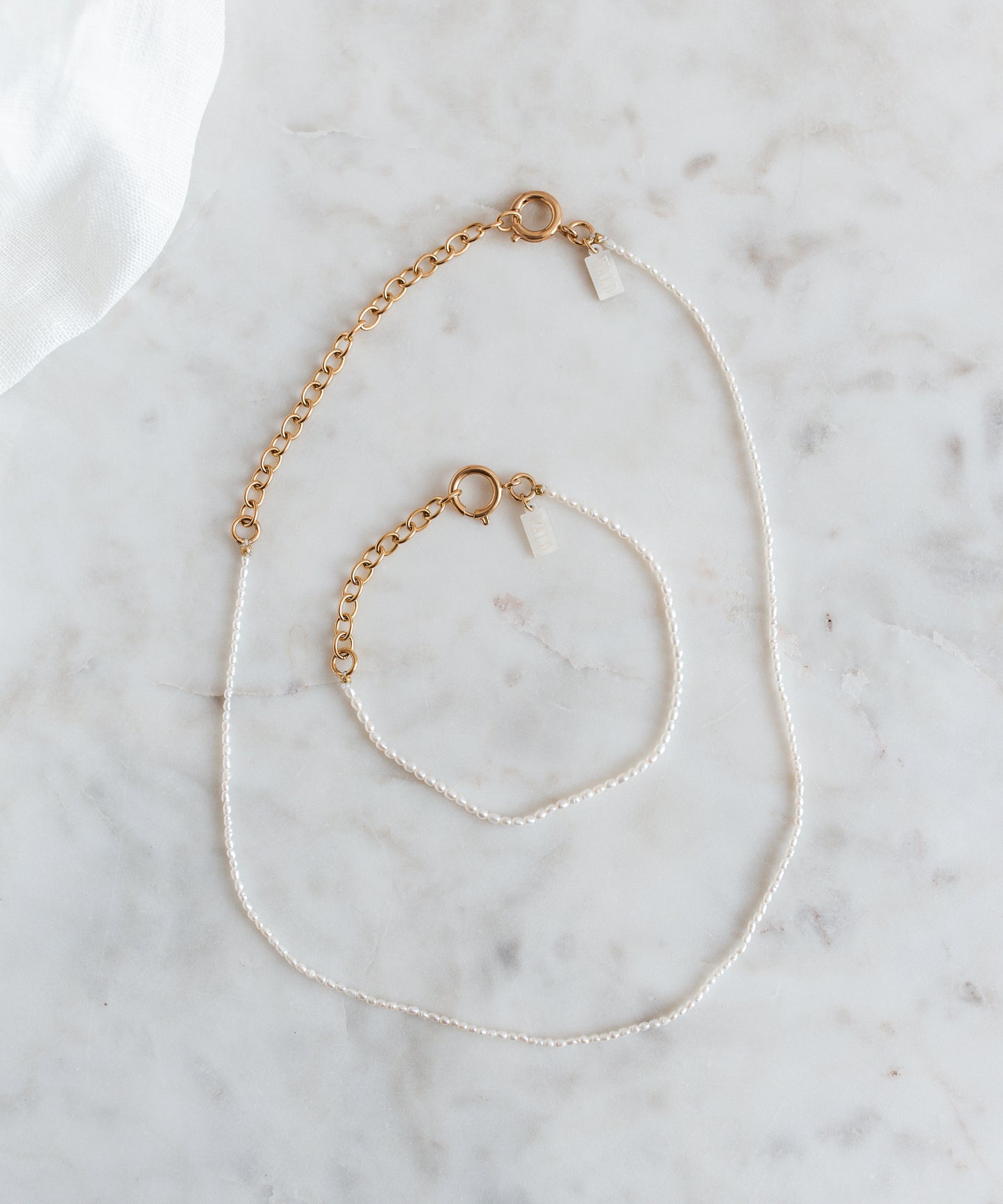 A WALD Berlin jewelry necklace with fine rice pearls displayed on a marble table in Germany.