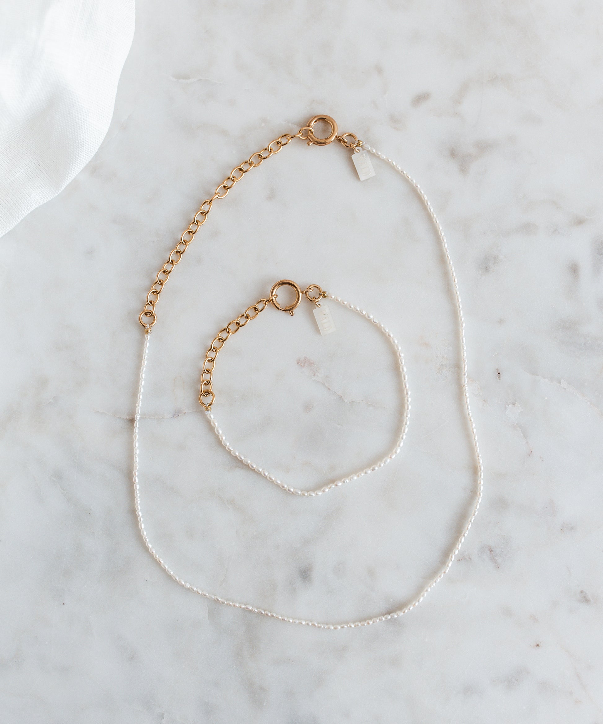 A WALD Berlin jewelry necklace with fine rice pearls displayed on a marble table in Germany.