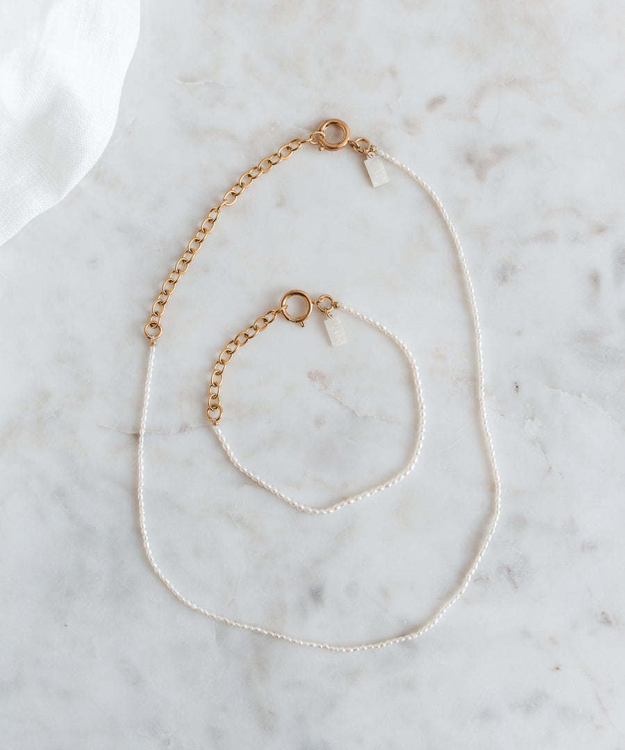 A WALD Berlin jewelry necklace with fine rice pearls displayed on a marble table in Germany.